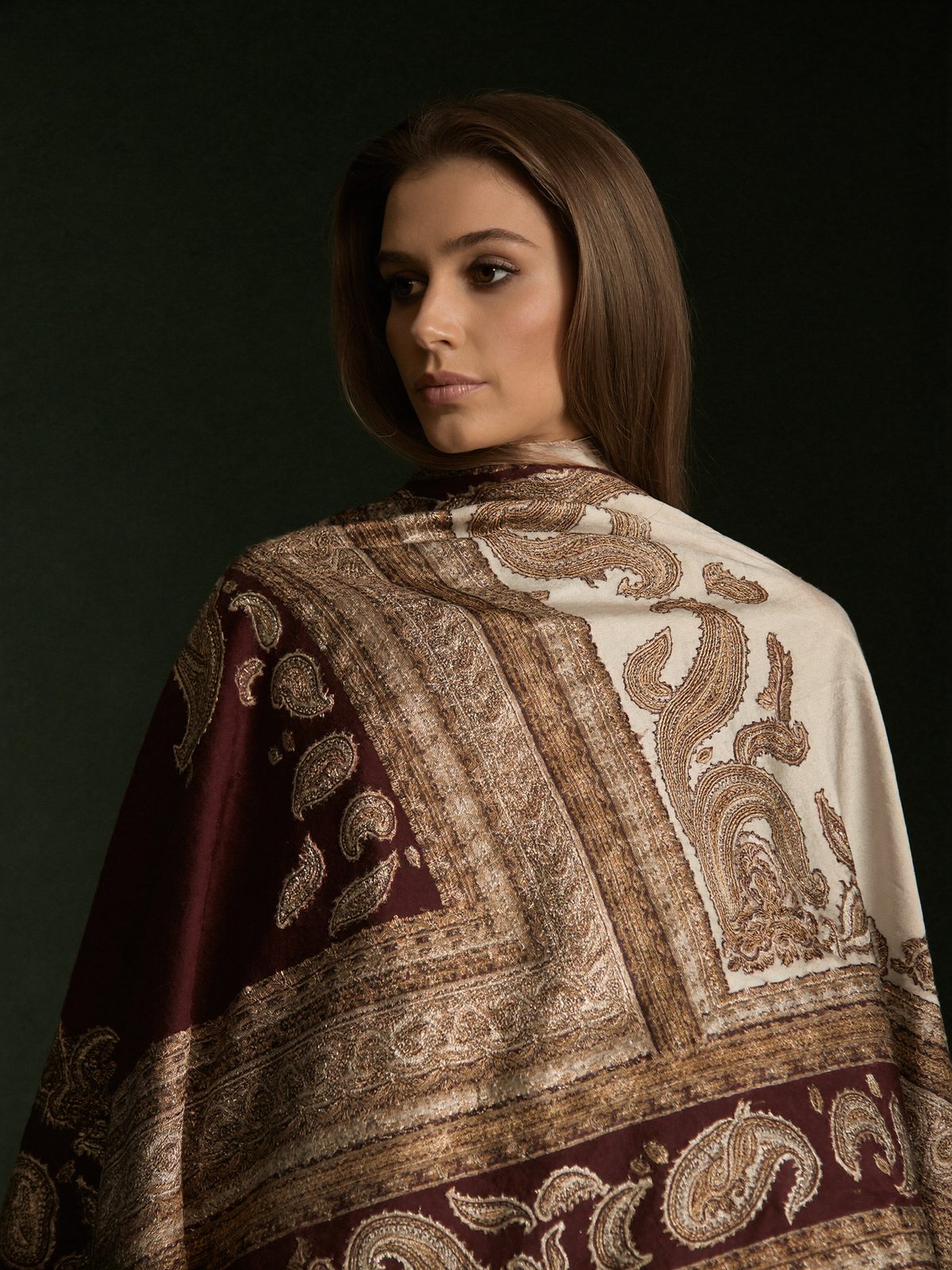 Woman wearing an embroidered Kashmiri shawl in burgundy, ivory and gold